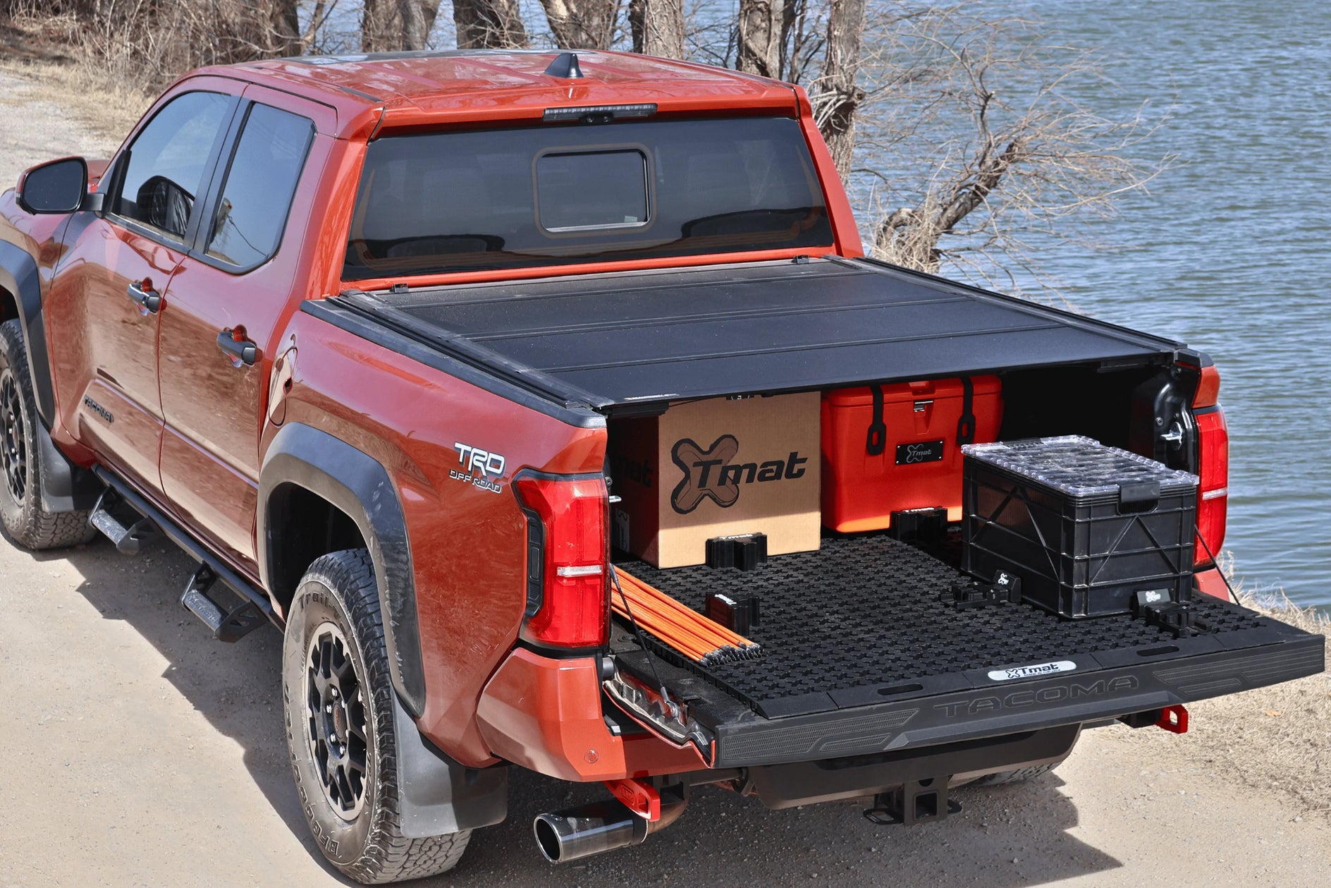 Red pickup truck with a tonneau cover and cargo in a natural setting